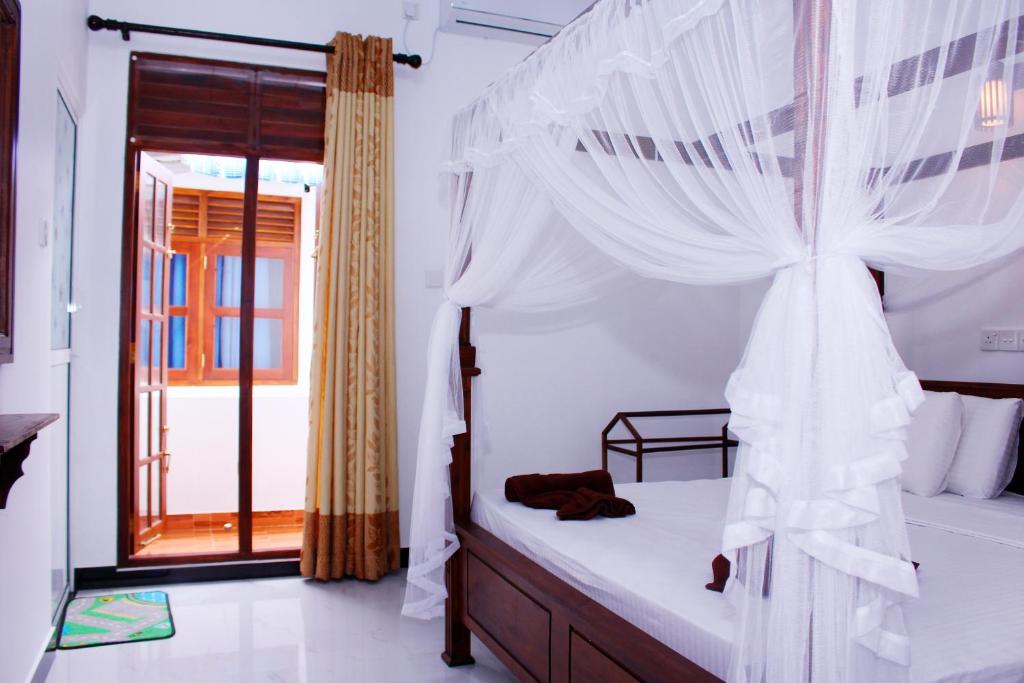 a bedroom with a canopy bed with a window at Amal Guest house in Mirissa