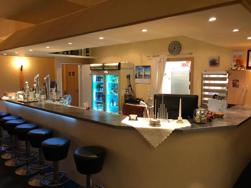 a bar with stools in a room with a counter at Schleswig Holstein Hotel in Elmshorn