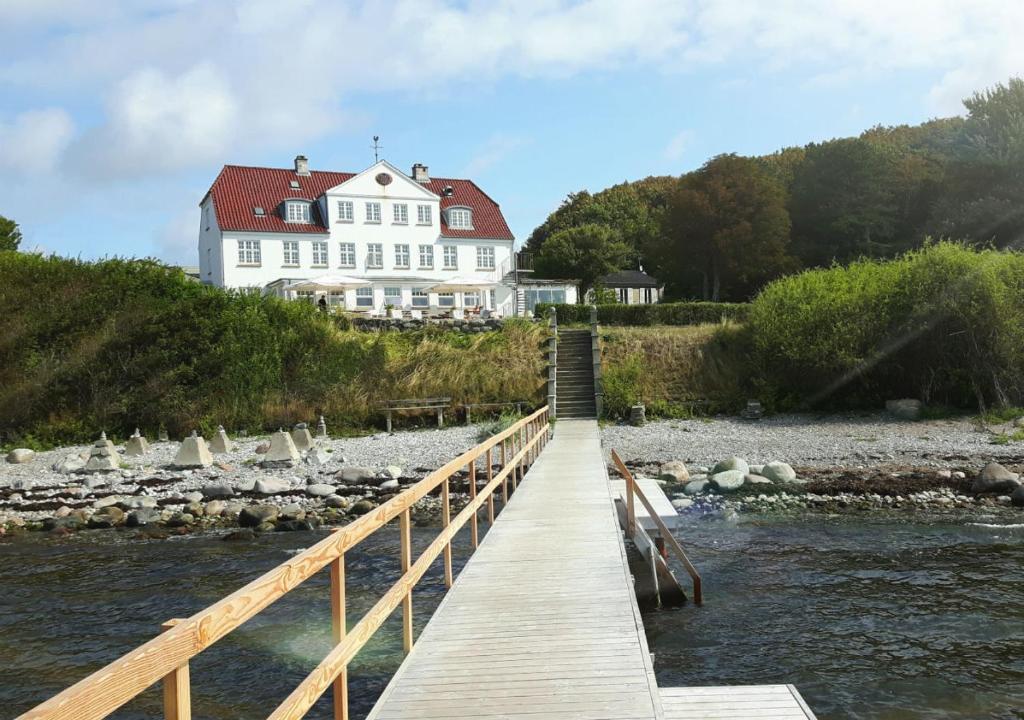 a bridge over a river with a large white house at Strandhotel Røsnæs in Kalundborg