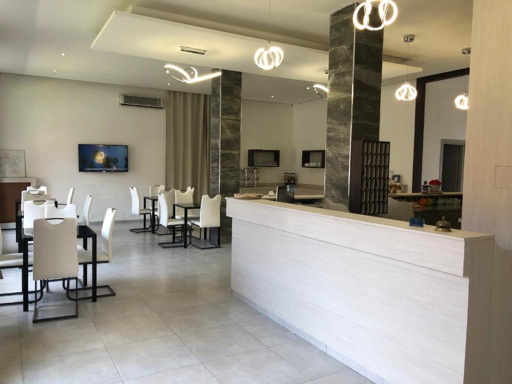 un restaurante con un bar con mesas y sillas blancas en Hotel Frejus, en Collegno