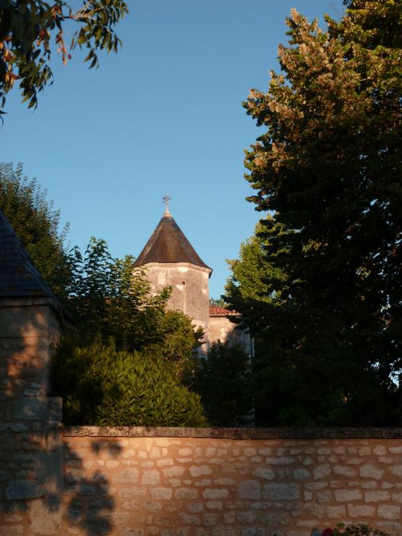 un bâtiment derrière une clôture en pierre avec un arbre dans l'établissement La laiterie du Logis, à Chaniers