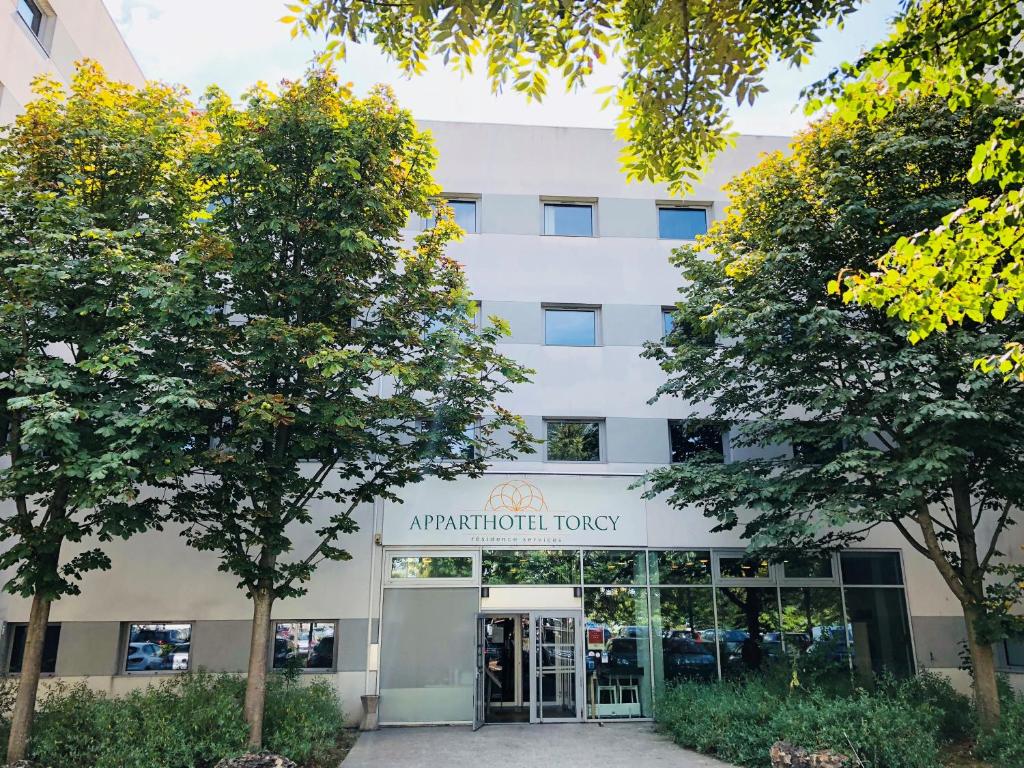 an apartment building with trees in front of it at Apparthotel Torcy in Torcy