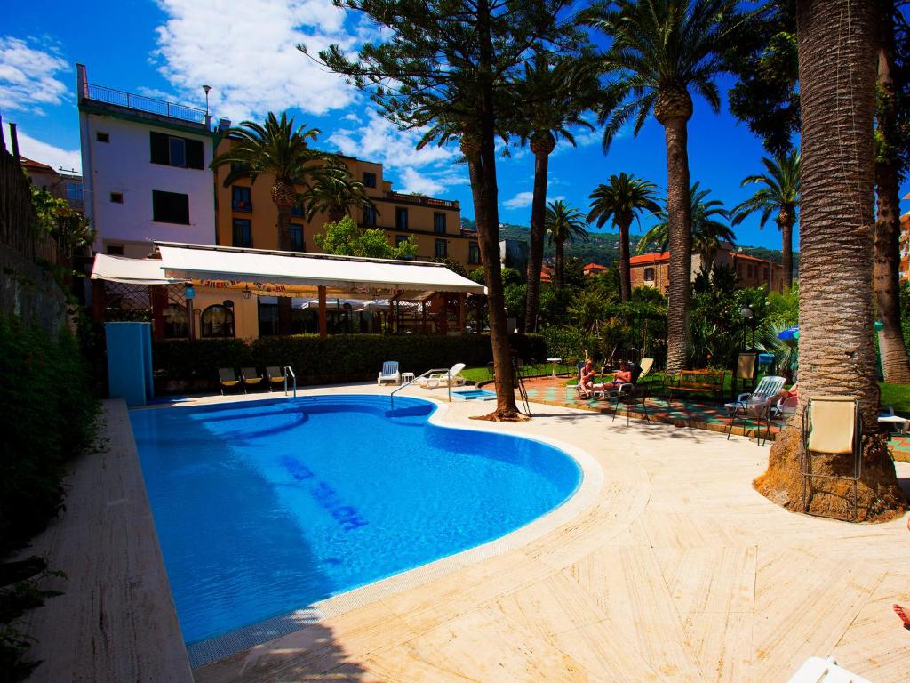 a swimming pool with palm trees and a building at Hotel Eden in Sorrento