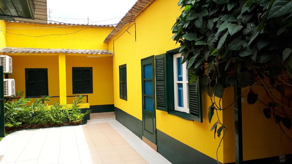 ein gelbes Haus mit grünen Rollläden drauf in der Unterkunft Residencialdes in São Tomé