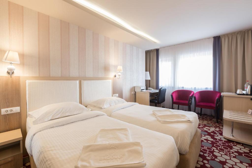 a hotel room with two beds and a desk at Bacolux Craiovita Hotel & Events, Craiova in Craiova