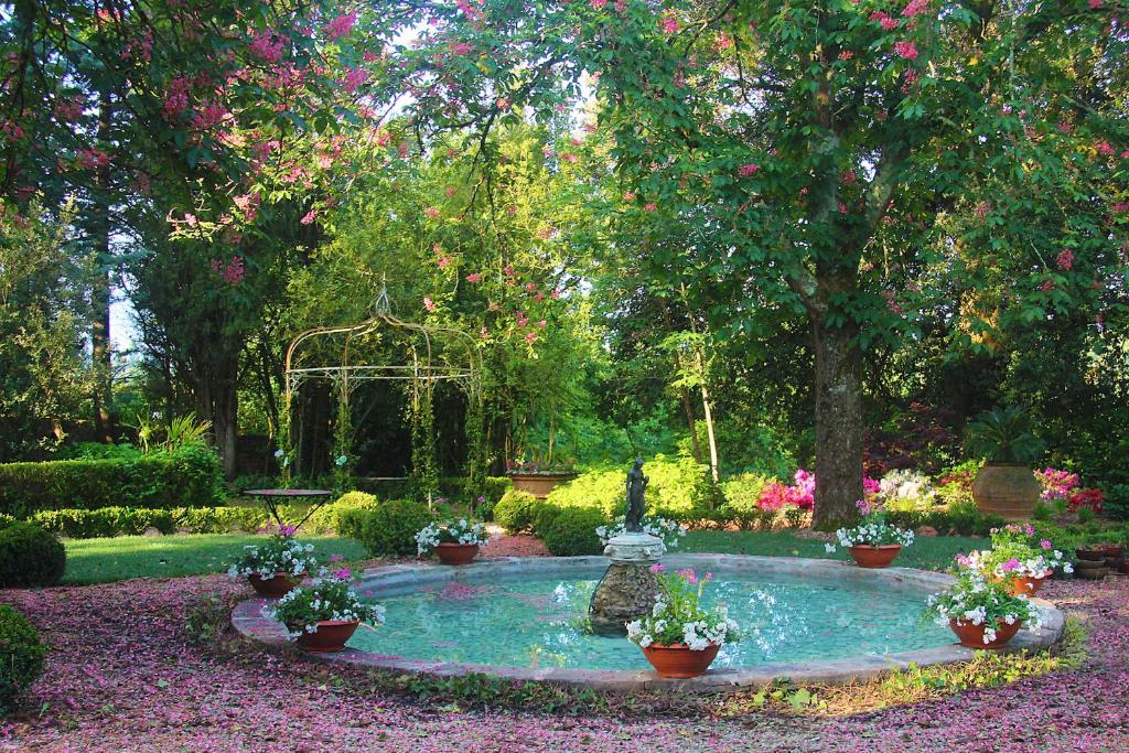 a garden with a small pond with flowers and a fountain at La Striscia Wine Resort in Arezzo