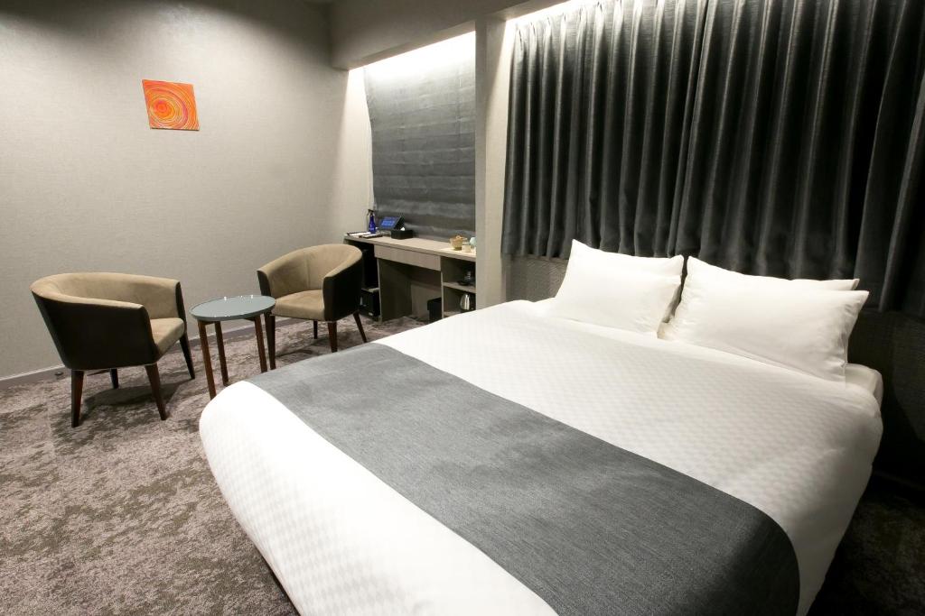 a hotel room with a bed and a desk and chairs at Hotel Banister Kyoto in Kyoto