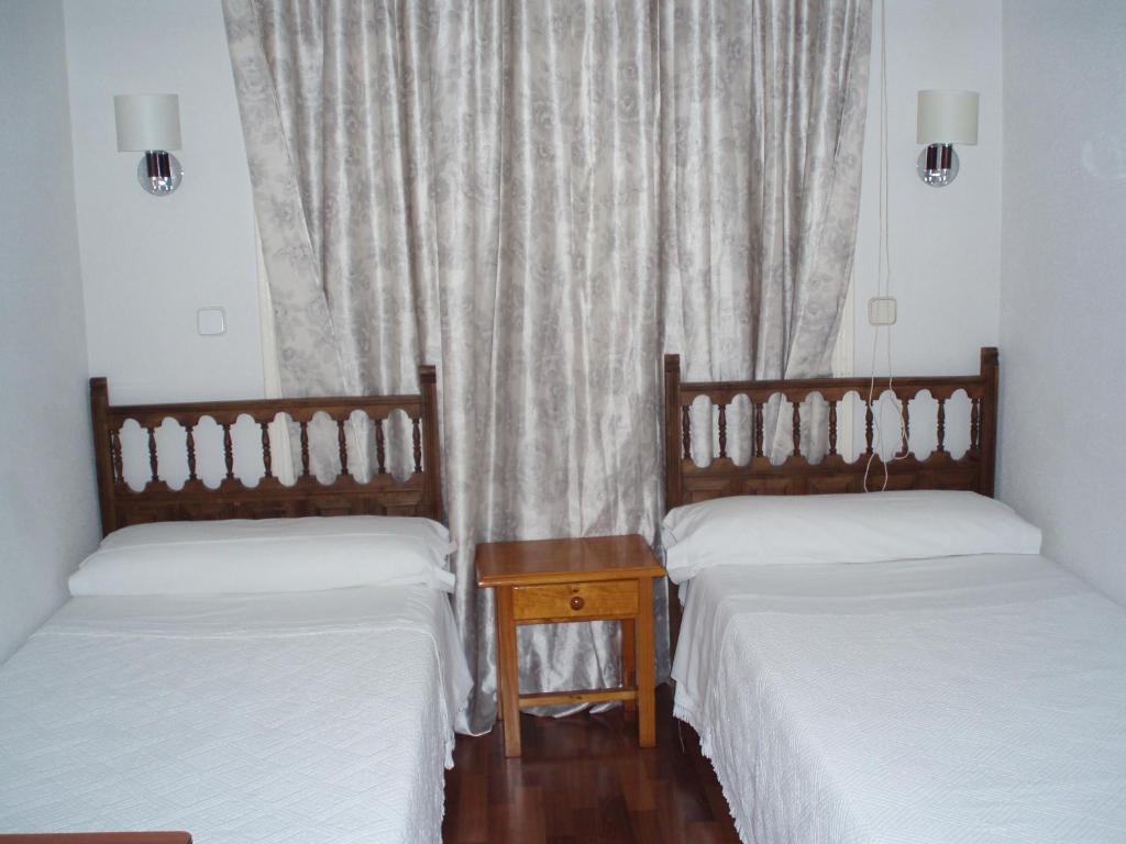 two twin beds in a room with a window at Hostal Castilla in Madrid