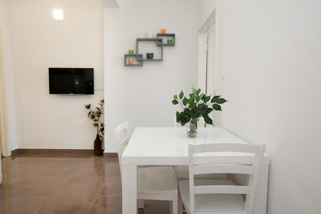 uma sala de jantar branca com uma mesa e cadeiras brancas em Apartman 1 em Zadar