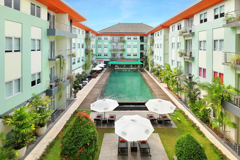 an aerial view of an apartment complex with a pool with umbrellas at HARRIS Hotel & Residences Riverview Kuta, Bali - Associated HARRIS in Kuta