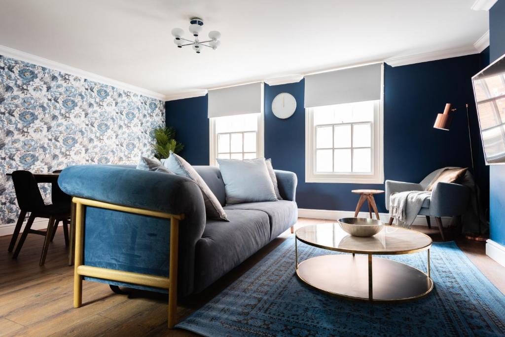 a living room with blue walls and a blue couch at The Old Station House - Stylish & Central 2BDR Apartment in Oxford