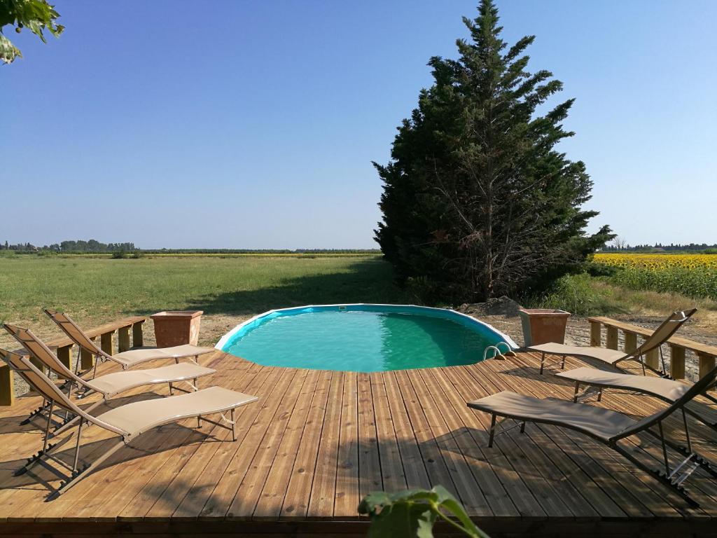 un grupo de sillas sentadas alrededor de una piscina en una terraza de madera en Mas des Prépresses - la Maison des vendangeurs en Beaucaire