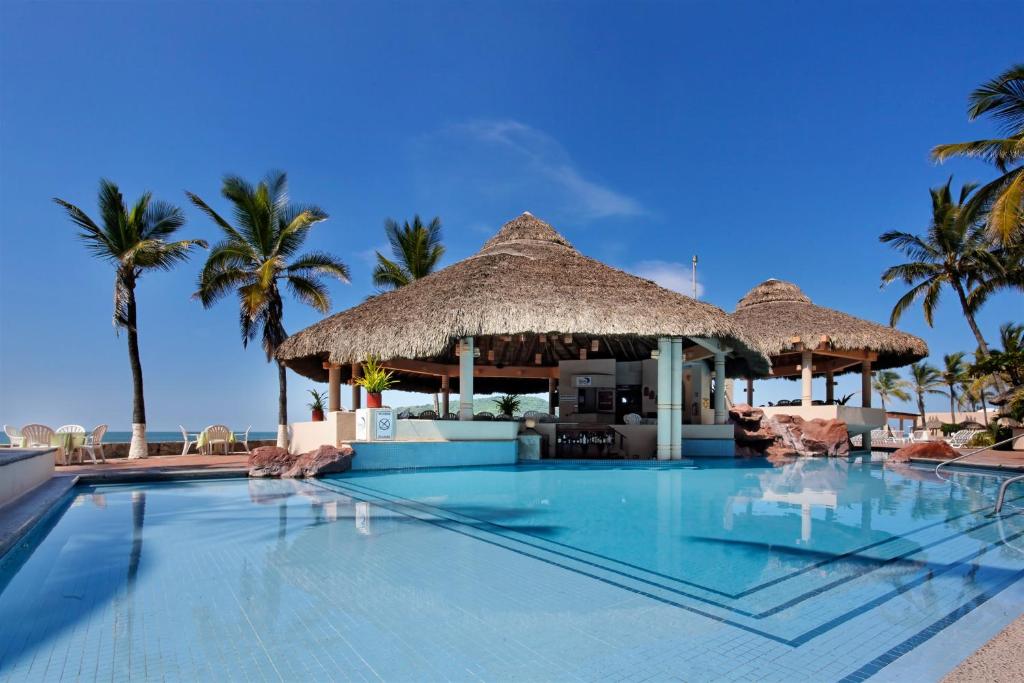 a swimming pool at a resort with palm trees at The Palms Resort of Mazatlan in Mazatlán