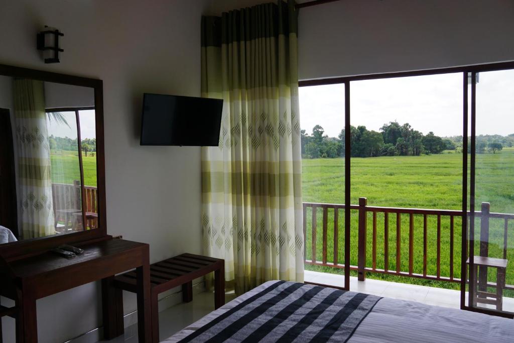a bedroom with a bed and a balcony with a television at Sunshine Tourist Rest in Anuradhapura
