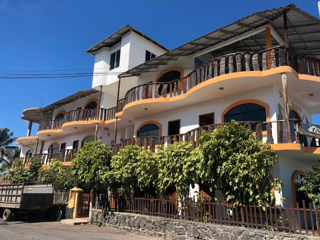 a large white building with a large balcony at Hostal Sandrita in Puerto Villamil