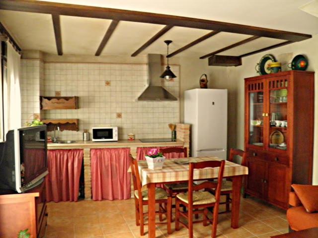 a kitchen with a table and a white refrigerator at Rincón del Valle del Jerte in Navaconcejo