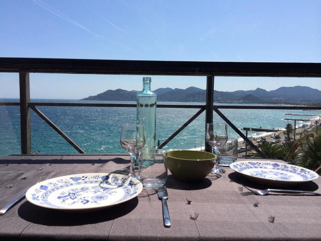 - une table avec des assiettes, des verres à vin et une bouteille dans l'établissement Cannes - view Cap Esterel, à Cannes