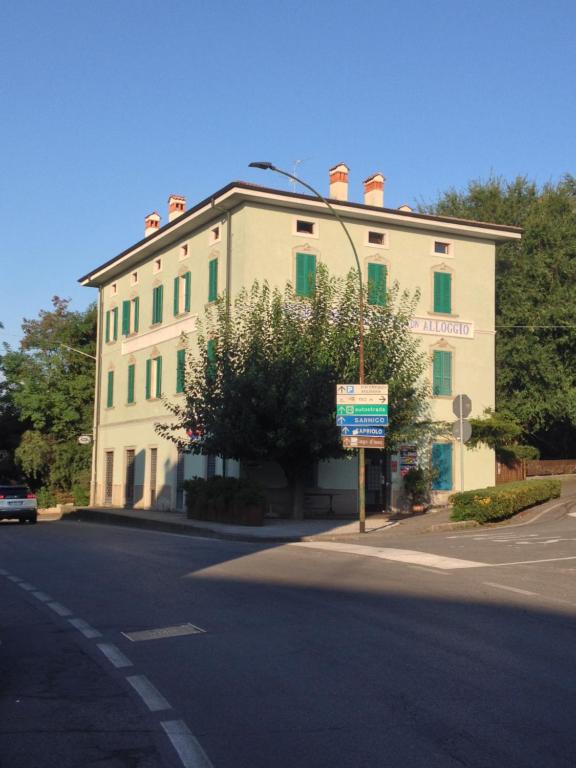Alloggio della Villetta في بالاتسولو سول أوليو: مبنى ابيض كبير شبابيكه خضراء على شارع
