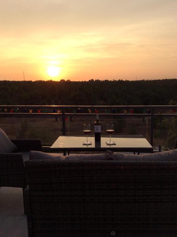 Paradise Terrace House في Quinta do Conde: كأسين من النبيذ يجلسون على طاولة مع غروب الشمس