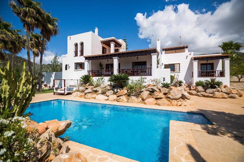 una casa con piscina frente a una casa en Villa Ca na Vinya en Cala Tarida