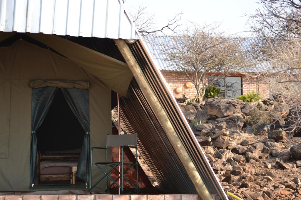 a tent with a chair sitting inside of it at Tana Safaris Bush Camp in Otjiwarongo