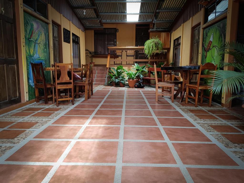 Habitación vacía con mesas, sillas y suelo de baldosa. en Greemount Hotel, en Monteverde