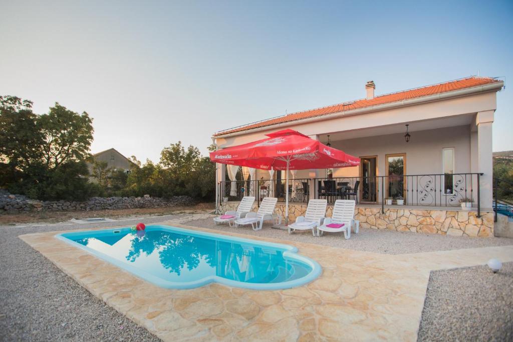a house with a swimming pool and a red umbrella at Holiday home with pool Kristal in Šibenik