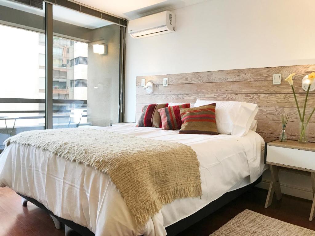 Un dormitorio con una gran cama blanca y una ventana en Vitacura Grove, en Santiago