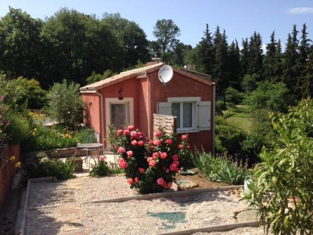 uma pequena casa com um arbusto de flores em frente em maison aubenas le lavandin em Ucel