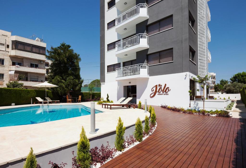 an apartment with a swimming pool and a building at The Jolo in Limassol