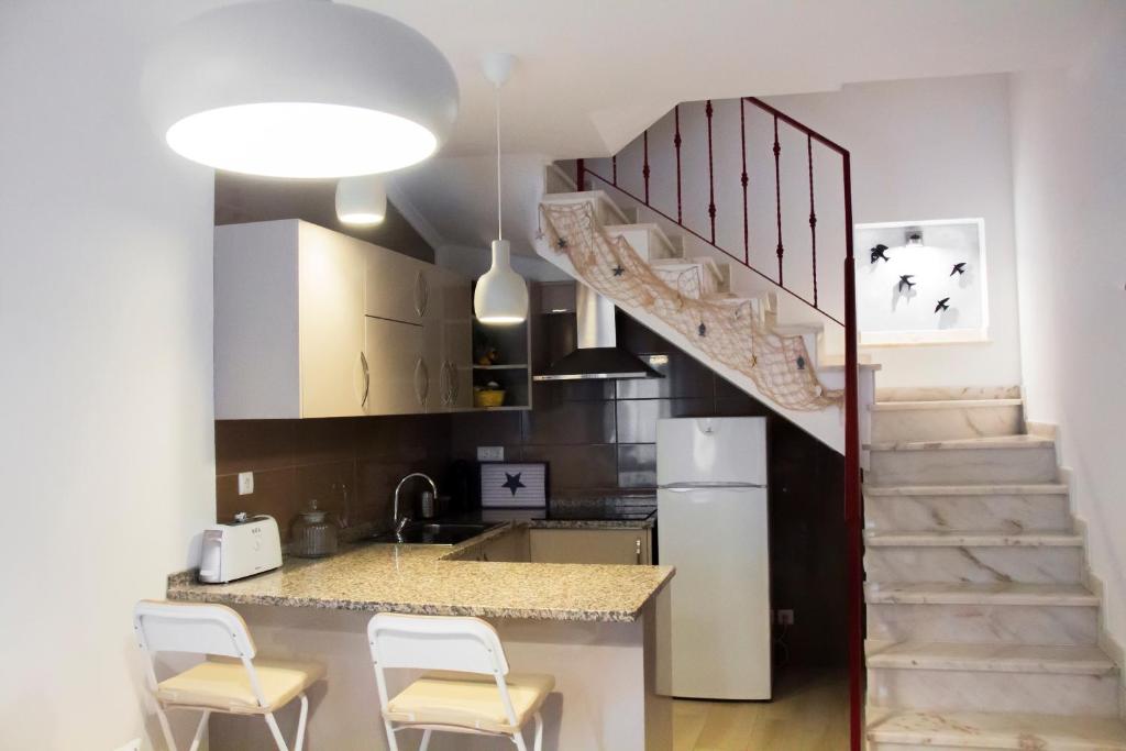 a kitchen with a staircase and a kitchen with chairs at Casa das Andorinhas in Lagos