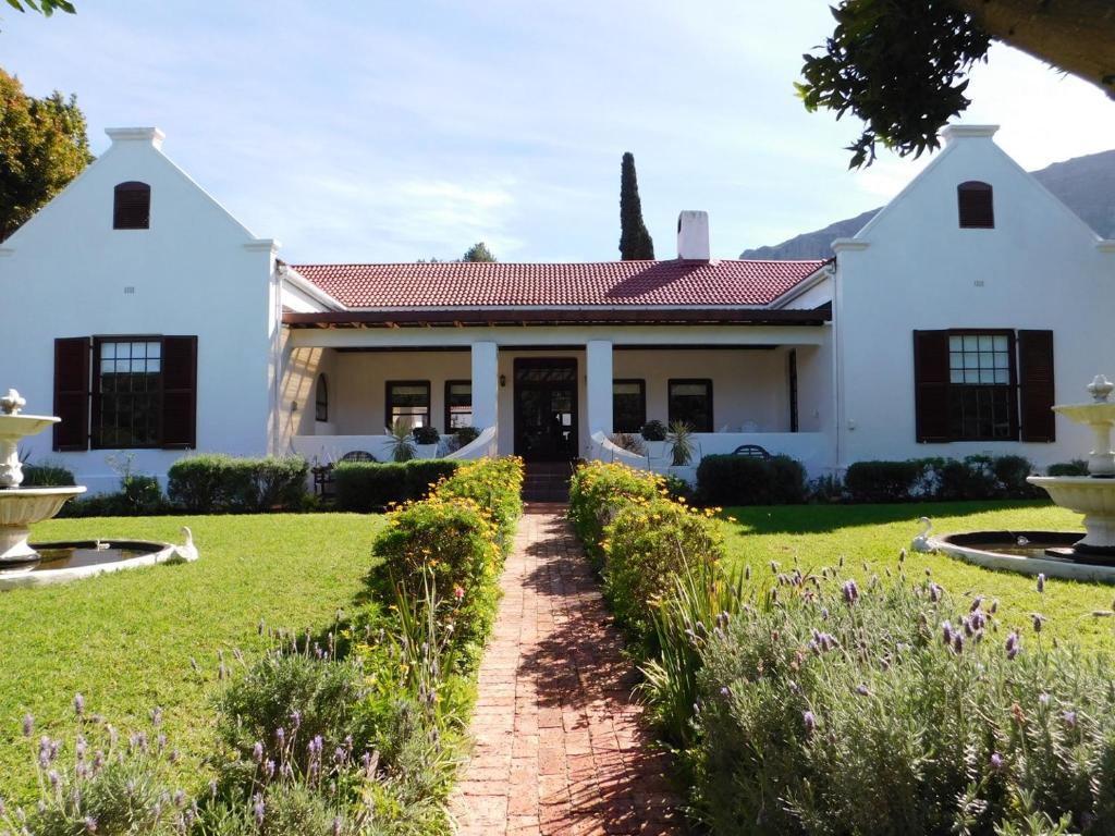 a white house with a lawn and flowers at Anoud Manor in Hout Bay