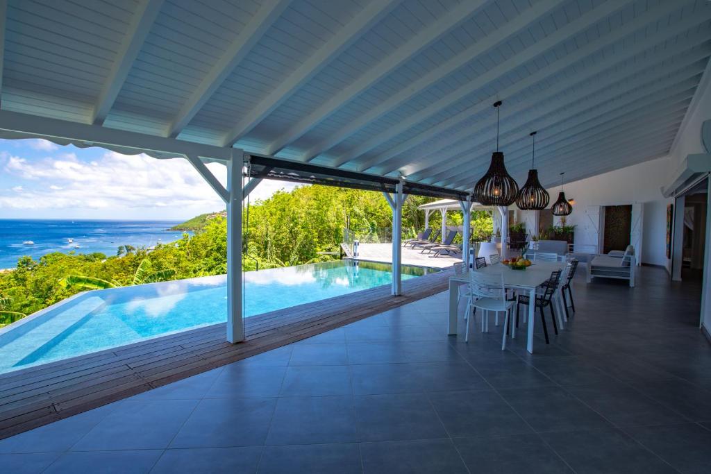 a villa with a swimming pool and a dining room at Sunset Bay - villa de luxe avec magnifique vue Ilets Pigeon in Bouillante