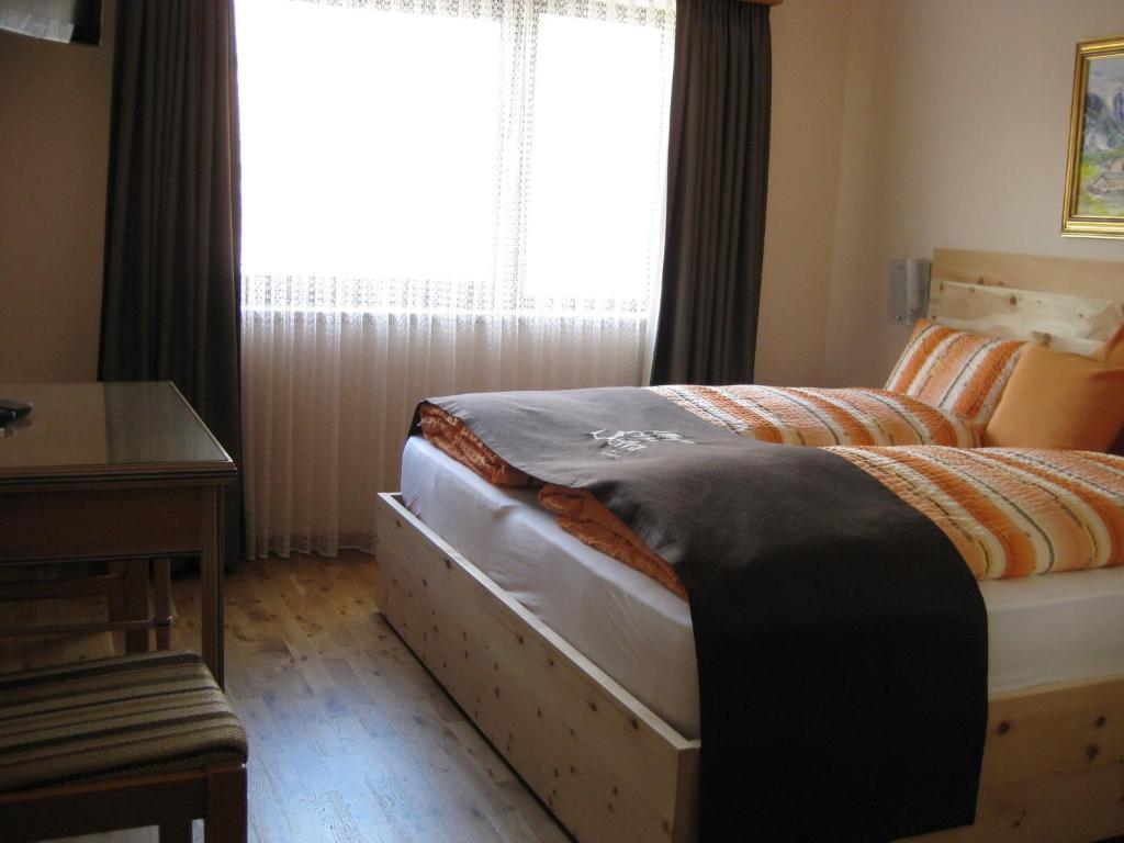 a bedroom with a bed and a desk and a window at Hotel Pizzeria Selva in Zernez