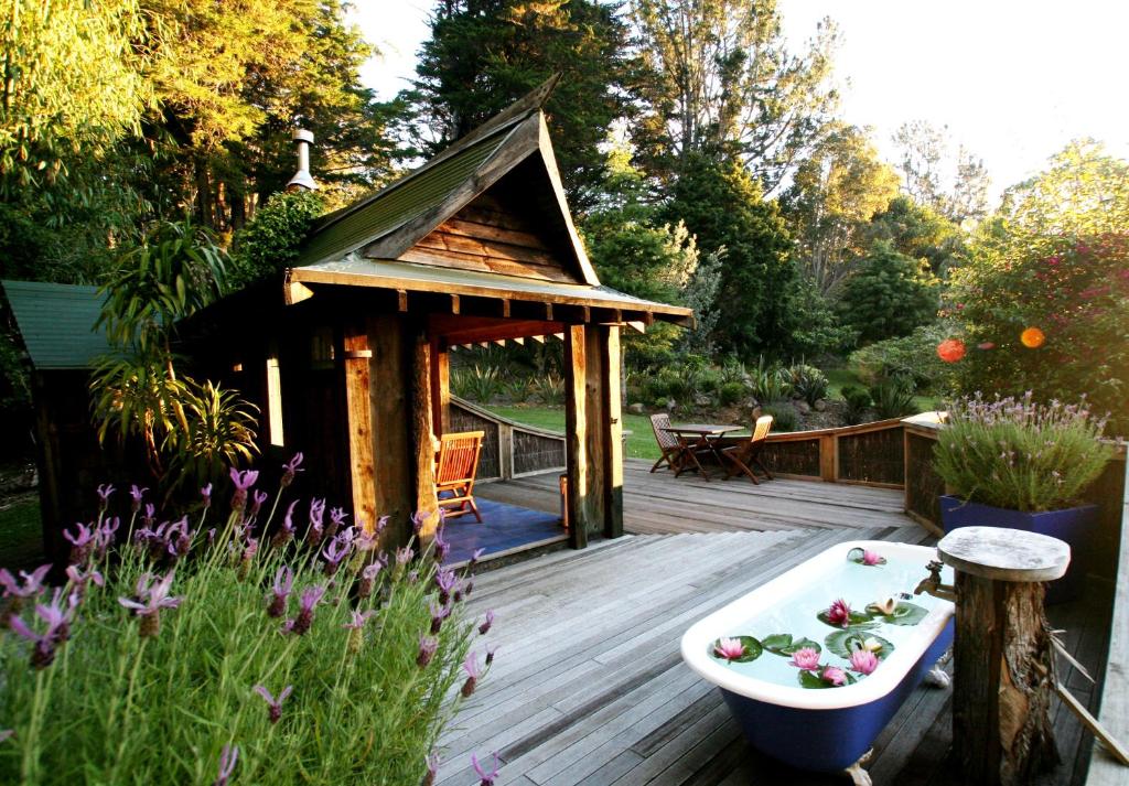 a wooden deck with a bath tub and a gazebo at Magic Cottages at Takou River in Kerikeri