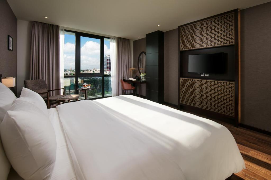 a large white bed in a hotel room with a flat screen tv at Grandiose Hotel & Spa in Hanoi