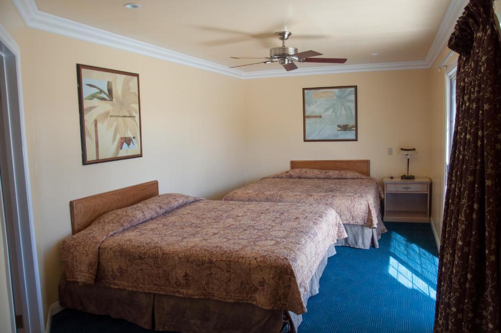a bedroom with two beds and a ceiling fan at Bayshore Inn Ventura in Ventura
