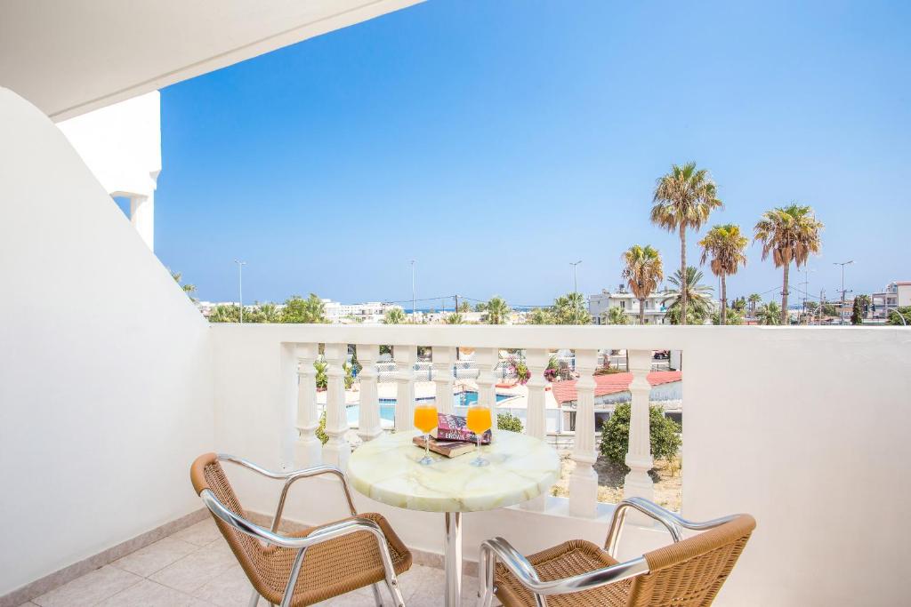 a white balcony with a table and two chairs at Iatridis Studios Faliraki in Faliraki