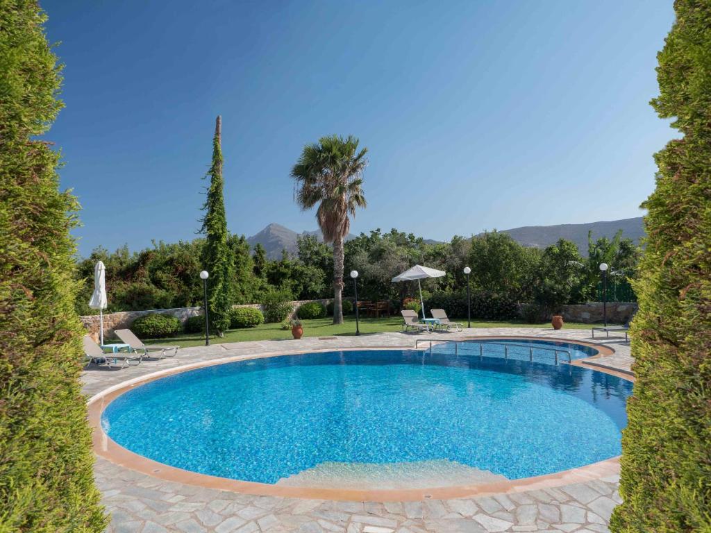 a swimming pool in a yard with a palm tree at Petritos Rooms and Studios in Falasarna