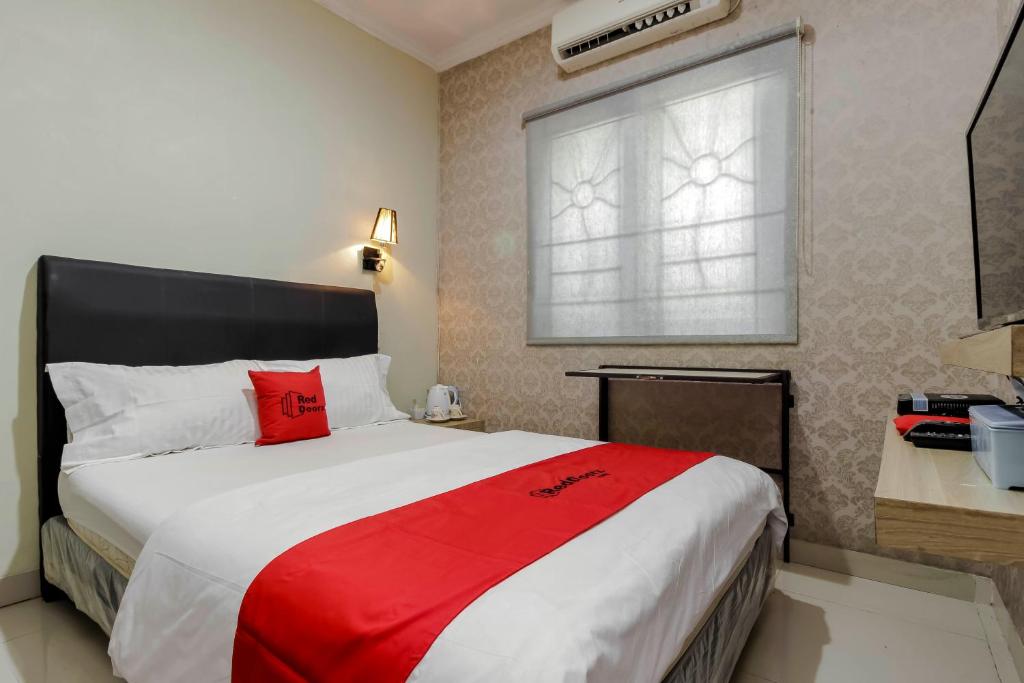 a bedroom with a large bed with a red blanket at RedDoorz Plus near Lippo Cikarang Mall in Bekasi
