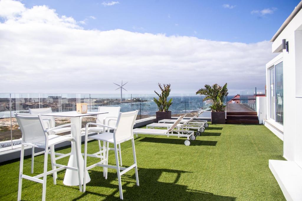 patio z białymi krzesłami i stołem na dachu w obiekcie Futura Apartment w Corralejo