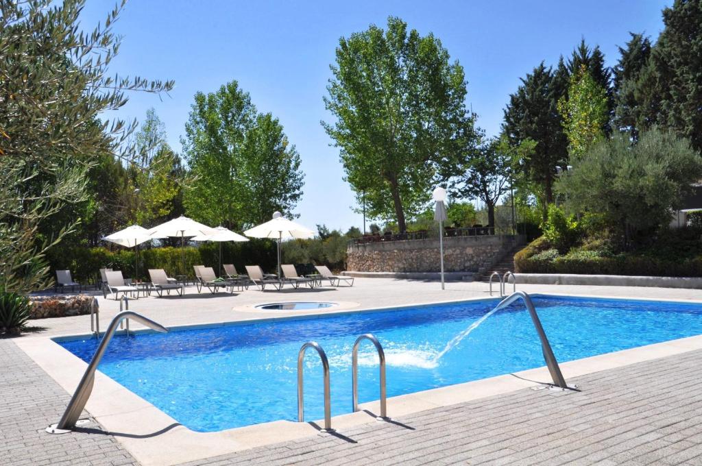 uma piscina com cadeiras e guarda-sóis em La Fuensanta Hostal-Rural em Horche