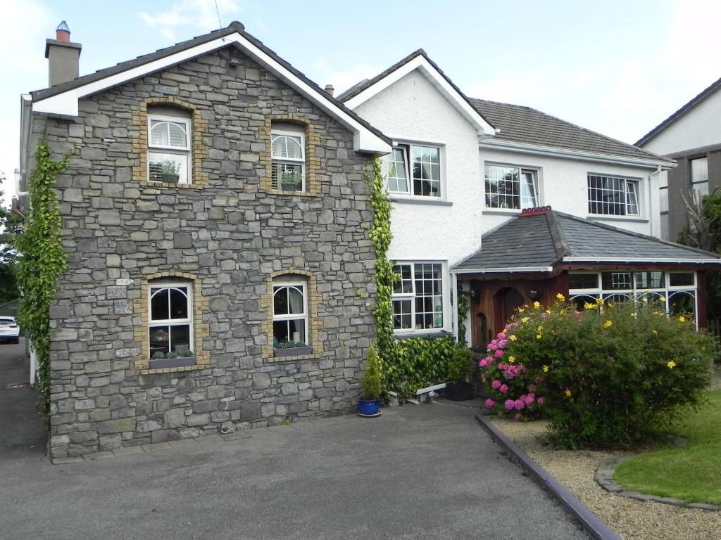 una casa con un edificio in pietra in un vialetto di Pearse Lodge a Sligo