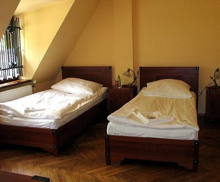 two beds in a room with a wooden floor at Dworek Cieszyński in Cieszyn