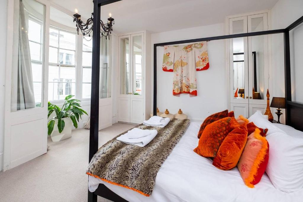 ブライトン＆ホーブにあるBeautiful townhouse with 4 poster bed & balconyのベッドルーム(オレンジ色の枕が付いた大きな白いベッド付)