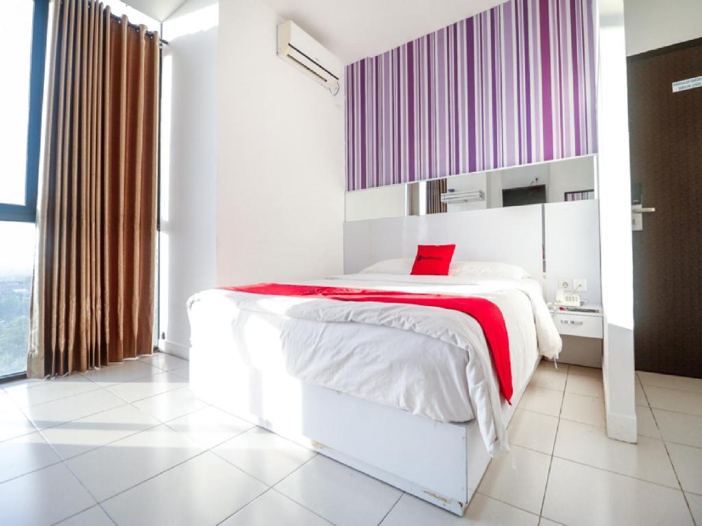 1 dormitorio con cama blanca y manta roja en RedDoorz near Terminal Batu Ampar, en Balikpapan
