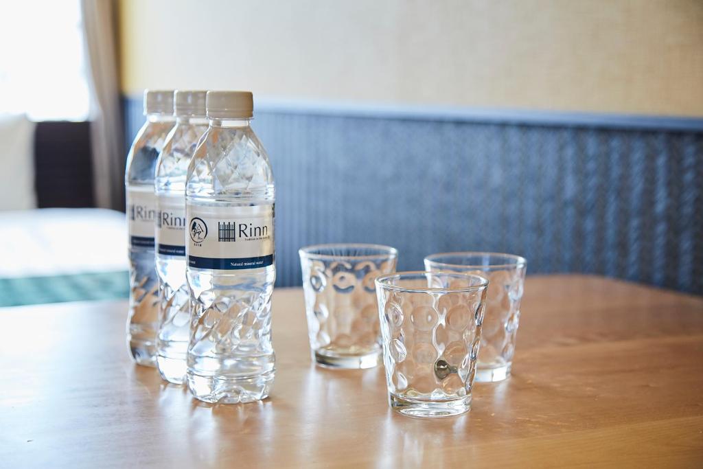 a bottle and two glasses on a wooden table at Rinn Gion Kenninji in Kyoto