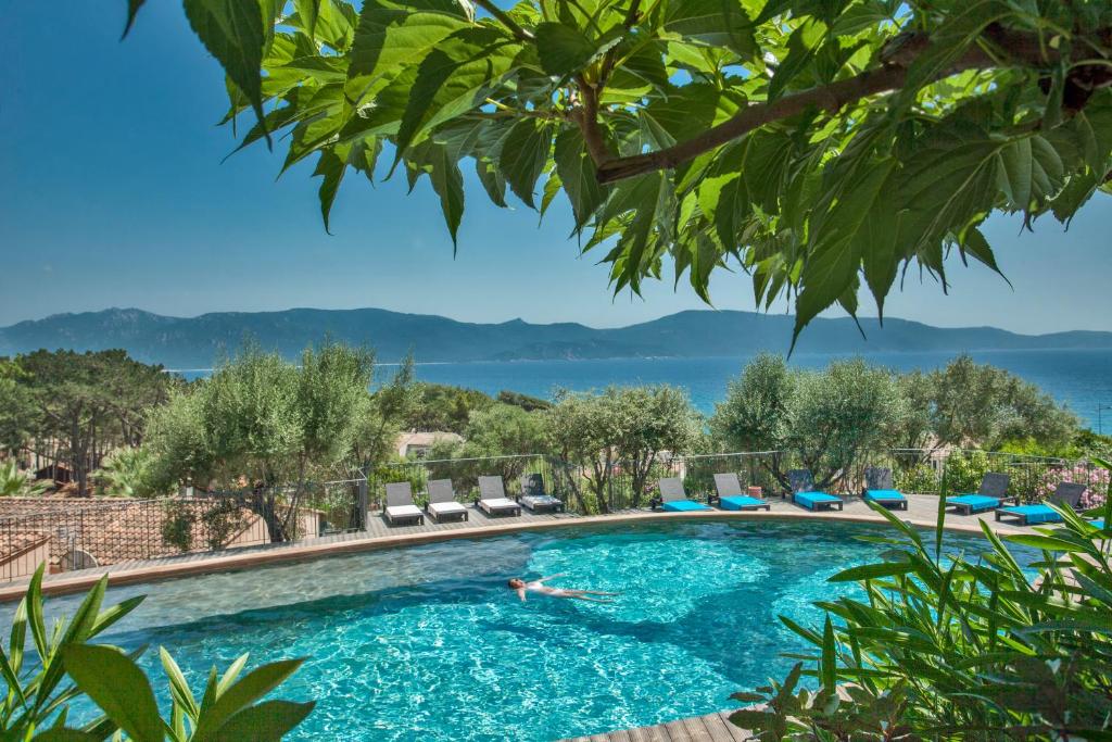 a person swimming in a pool with a view of the water at Résidence Cantu di Mare in Olmeto