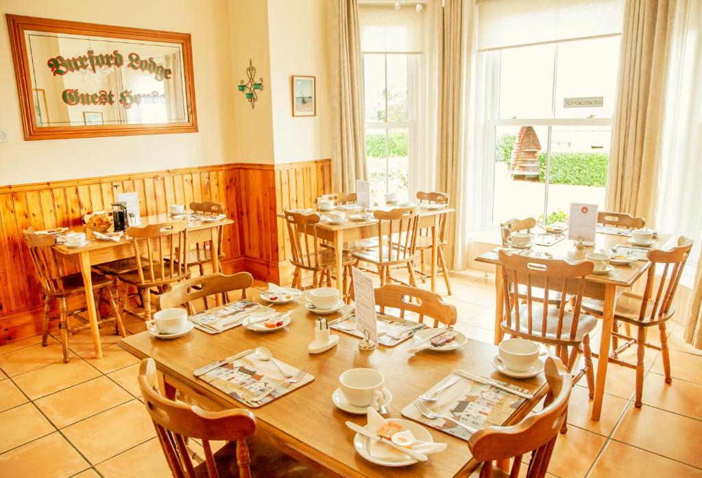 un comedor con mesas y sillas y una gran ventana en Burford Lodge Guest House, en Ardglass