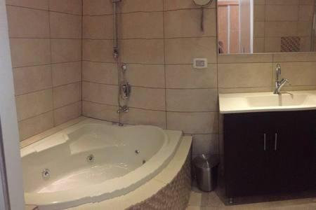 a bathroom with a bath tub and a sink at Charmin apartment whit a big garden in Haifa